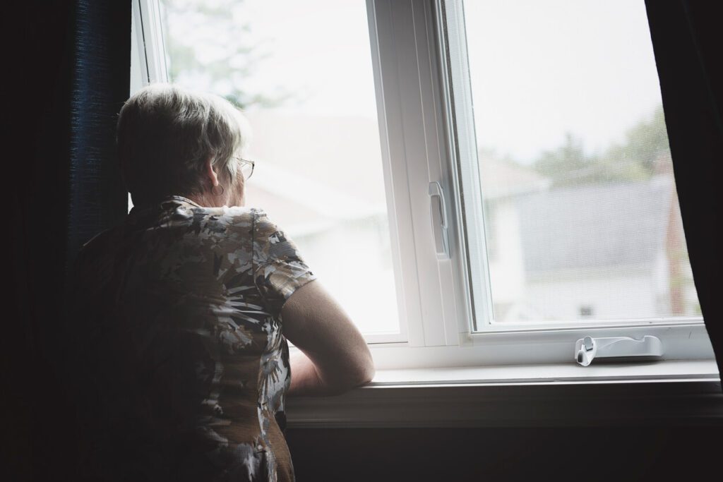 Elderly woman who's sad looking out window