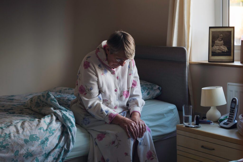 elderly woman sad on her bed
